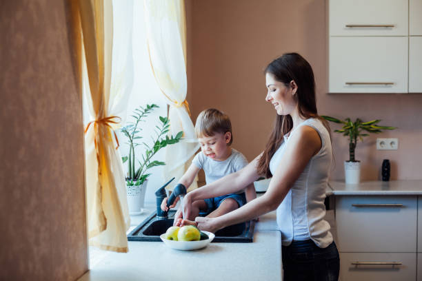 キッチンママの息子は果物や野菜を洗う - minute maid beverages ストックフォトと画像