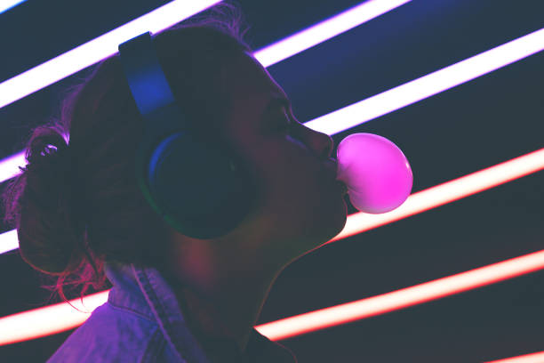 istock Millennial girl profile blowing bubble gum illuminated neon dark light. 1222069106