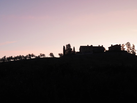 Silueta de una casa de campo y ciprés en una colina en la región de la Toscana de Italia, paisaje con fondo de amanecer. photo