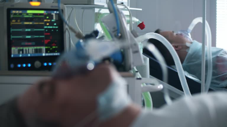 A man with ventilator lying in clinical ward during coronavirus pandemic.