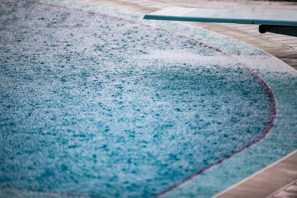 Empty Swimming Pool With Diving Board During Rain stock photo