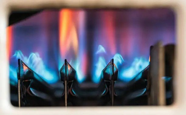 Flames ignited to heat water as seen through a gas boiler's viewing window.