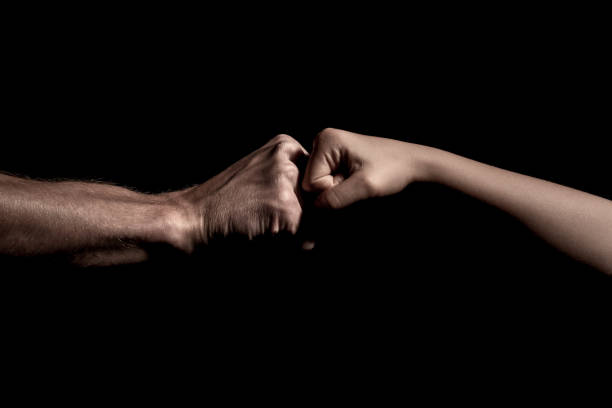 two hands fist bump together over black background