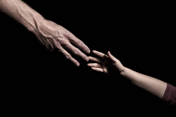 istock Hands reaching out to each other on dark black background 1222075389