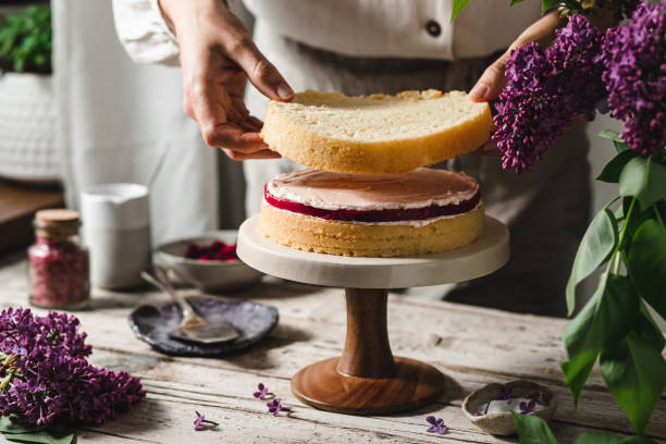 plan rapproché du chef féminin préparant le gâteau en couches - crème au beurre photos et images de collection