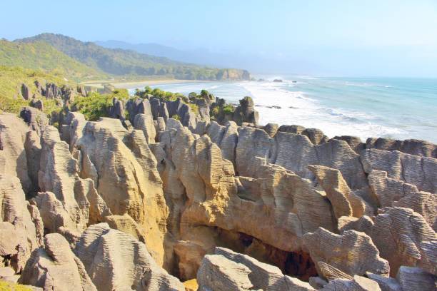 Scenic, wild Pancake Rocks at Punakaiki in New Zealand Scenic coast with wild rock formations called Pancake Rocks at Punakaiki in New Zealand with a nice long beach in the background. punakaiki stock pictures, royalty-free photos & images