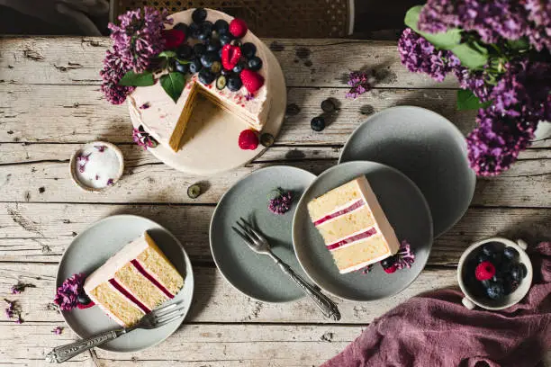 Top view of tasty fruit and flower cake served in plates over a wooden table.