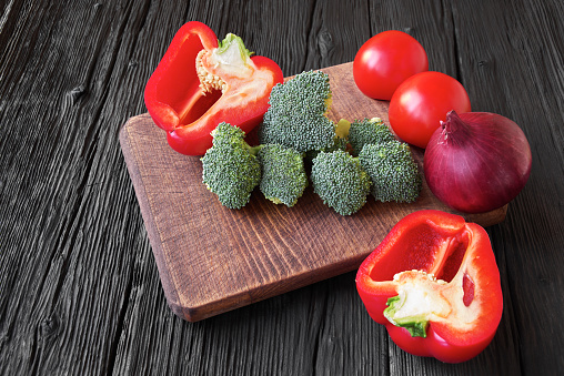 Various fresh ripe vegetables on cutting board, dark wooden background