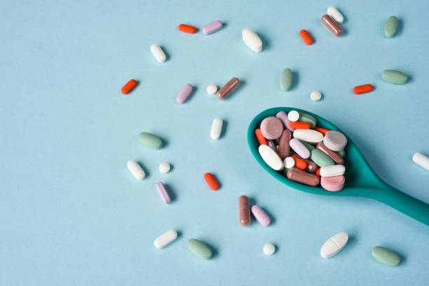 multi gekleurde pillen op een lepel - multi vitamine stockfoto's en -beelden