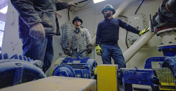 три мужчины нефтяников говорить и подготовиться к открытию / закрыть валки, чтобы изменить давление потока грязи в насосной комнате на нефт - mining engineer oil industry construction site стоковые фото и изображения
