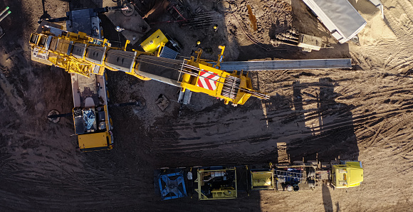 Directly Overhead Aerial Drone Shot of a Crane Breaking Down a Rig at an Oil and Gas Drilling Pad Site in a Valley on a Sunny Day