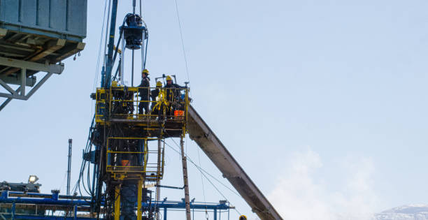 Oilfield Workers Service a Well on a Tall, Metal Platform at an Oil and Gas Drilling Pad Site on a Cold, Sunny, Winter Morning Oilfield Workers Service a Well on a Tall, Metal Platform at an Oil and Gas Drilling Pad Site on a Cold, Sunny, Winter Morning wellhead stock pictures, royalty-free photos & images