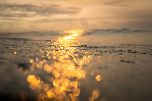 Golden reflection of sun on ocean surface with horizon