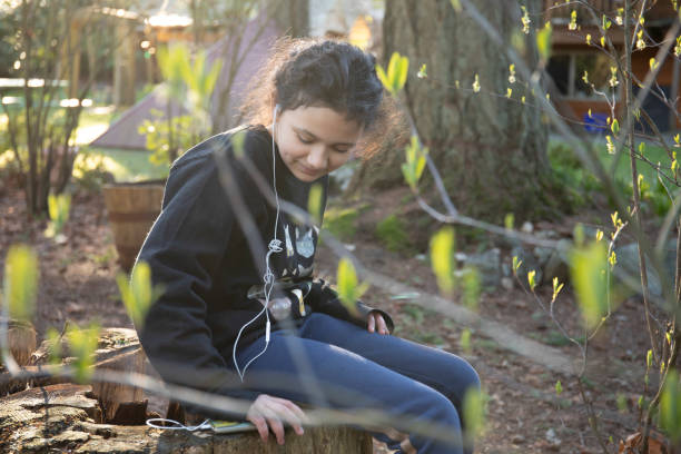 joven cita escucha música en el jardín - children only tree area exploration freshness fotografías e imágenes de stock