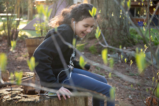 joven se ríe mientras escucha música en el jardín - children only tree area exploration freshness fotografías e imágenes de stock