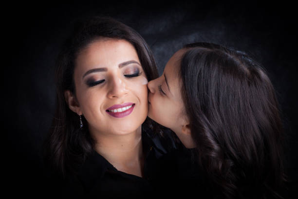mother getting a kiss from daughter mother getting a kiss from daughter. Daughter caressing her mother to celebrate Mother's Day. cute pregnant woman with gift stock pictures, royalty-free photos & images