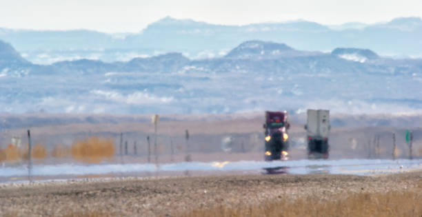 heat haze distorts vidéo de semi-trucks driving down a utah interstate surrounded by mountains on a sunny day - brume de chaleur photos et images de collection