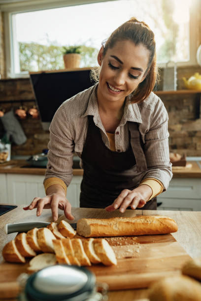 istock Happy woman using baguette while preparing food in the kitchen. 1222085070