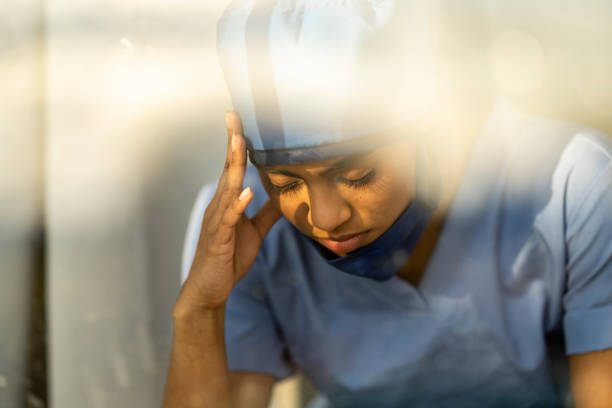istock Stressed Female Medical Professional Sitting Down Holding her Head 1222085092