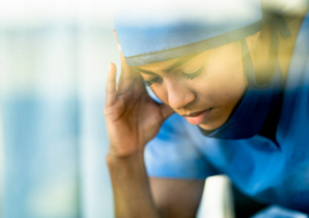istock Stressed Female Medical Professional Sitting Down Holding her Head 1222085101