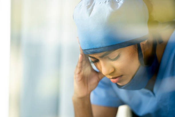 istock Stressed Female Medical Professional Sitting Down Holding her Head 1222085107