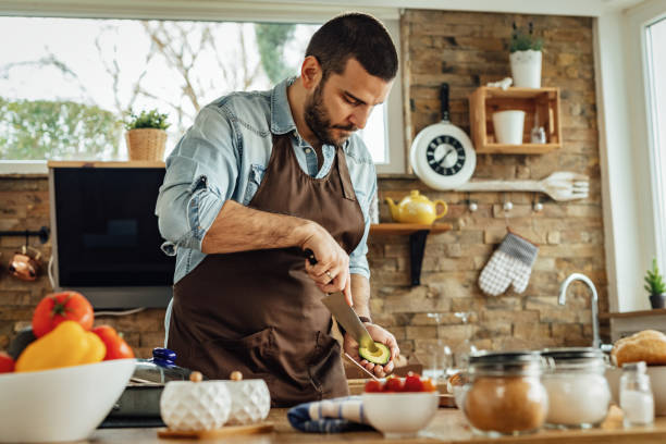 istock Young man peeling avocado while preparing a meal in the kitchen. 1222085865