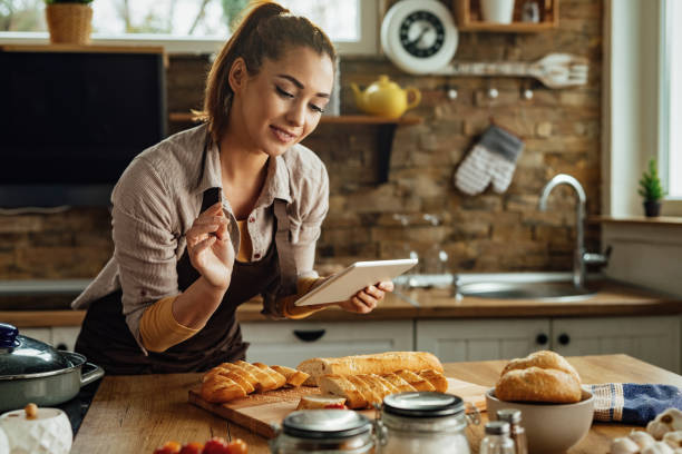 istock Young woman using digital tablet while preparing food in the kitchen. 1222085867