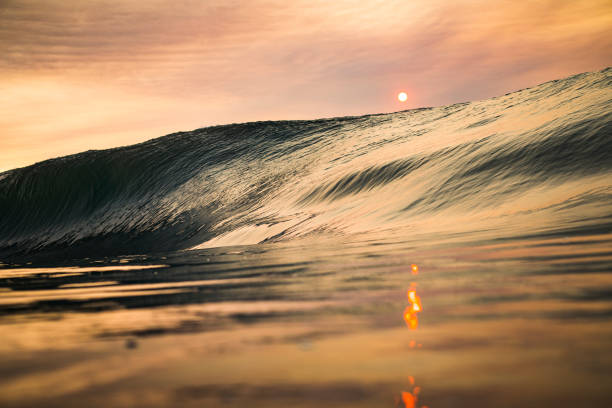 Orange sun and building wave in ocean with reflection