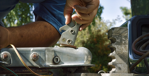 Close-Up Shot of a Hispanic Man's Hands Closing the Latch on the Trailer Coupler on a Sunny Day