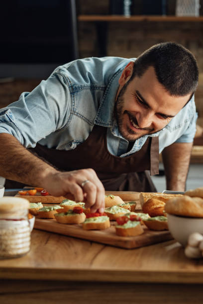 istock Young smiling man preparing bruschetta in the kitchen. 1222086298