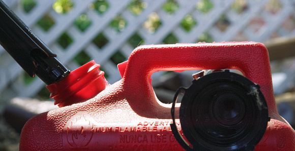Close-Up Shot of a Someone Pouring Gasoline into a Red, Plastic Gasoline Can Outdoors