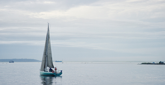 A Sailboat with a Small Crew Heading Out into Puget Sound in Washington on an Overcast Day