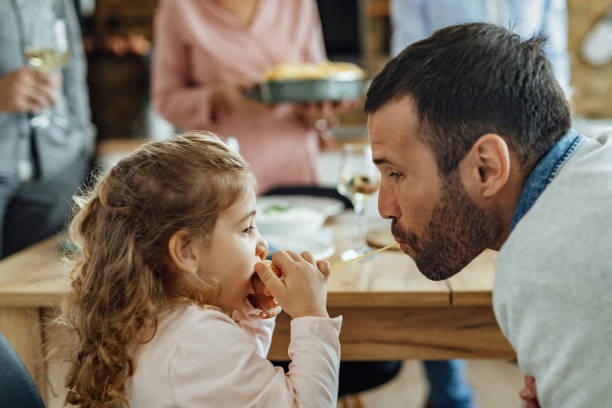 istock Father and daughter sharing a spaghetti while having lunch in dining room. 1222087458