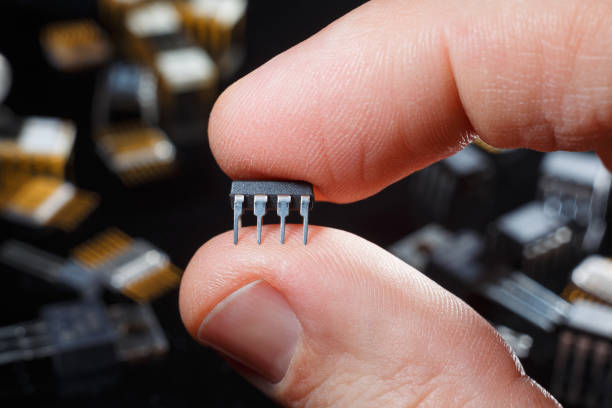 istock Electronic microchip with fingers close-up. Man hand holds microcircuit. 1222088016