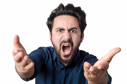 Portrait of a young man screaming with furious facial expression over white background. Horizontal composition. Studio shot.
