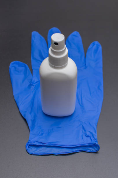 alcohol sanitizer and protection glove on dark surface