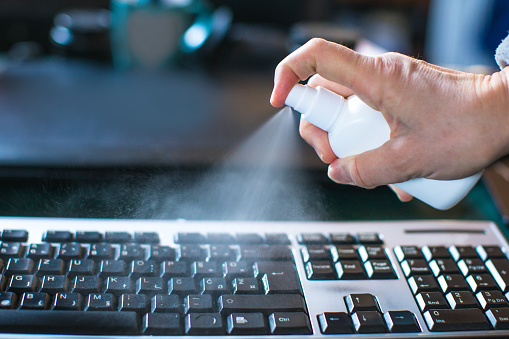 sanitizing computer keyboard with alcohol spray