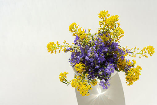 Spring flowers in a vase top view. Beautiful yellow and purple flowers in a glass vase. Flowers on a white background