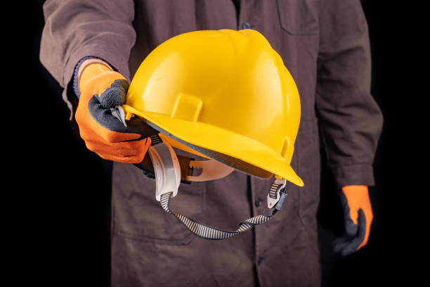 istock Production worker with work helmet in hand. A man dressed in work clothes. Dark background. 1222090917