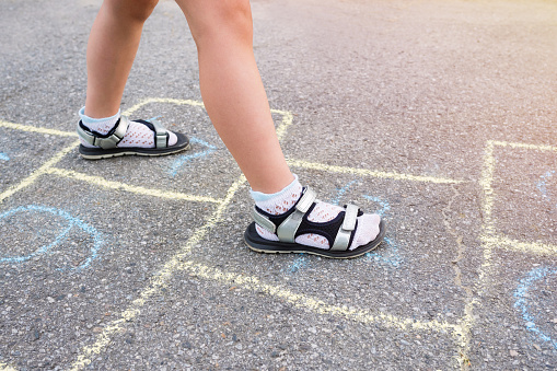 Children's feet and drawings with chalk on the pavement closeup.