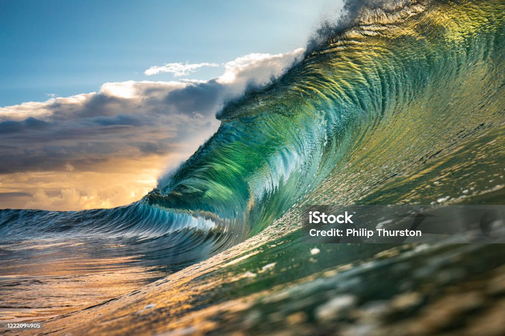 Powerful green wave breaking heavily in ocean Powerful green and gold wave breaking heavily in ocean over reef and rock Wave - Water Stock Photo
