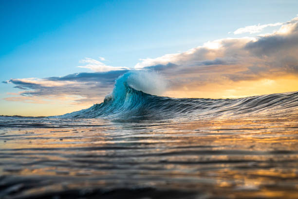 日の出の嵐でフレアにピークを迎えるカラフルな波 - waves crashing ストックフォトと画像