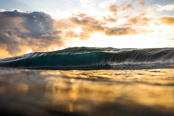 istock Smooth ocean waves breaking with bright golden sunrise 1222095011