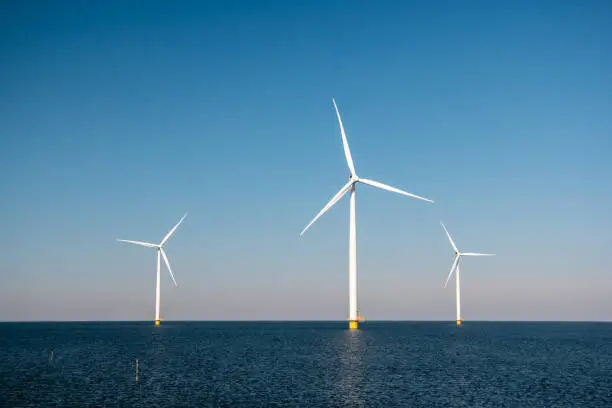 Photo of offshore windmill park green energy in the Netherlands Europe, wind mill turbines at sea and land providing green energy industry