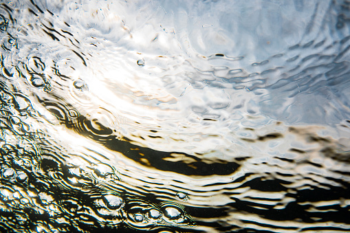 Patterns, bubbles and tension below the water surface with golden sunrise theme