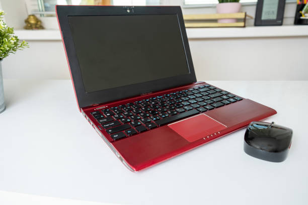 istock A modern red laptop and a mouse standing on white table, working space for business 1222099784