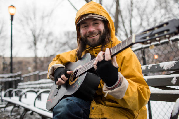 istock Musician sitting on a park bench busking for tips 1222101480