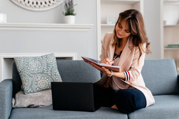 istock Happy young woman is working on comfortable couch and using laptop at home 1222106088