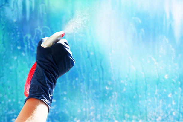 Washes window. Spray atomizer in female hand. Spray with a water jet close-up. Housework concept