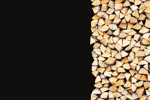 Woodpile of birch firewood isolated on black background